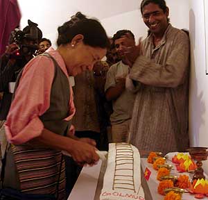 An elderly Tibetan cuts a cake representing the newly-opened Golmud-Lhasa railway line. Anup Scaria of Kashi next to her.