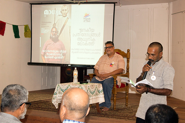 Friends of Tibet Campaigner Yelthdo Mathew welcomes with a Malayalam poem by Prof Madhusoodanan Nair literally translated as 'Who Is Gandhi'. The poem talks about seven major rivers of India - Ganga, Yamuna, Saraswathi, Sindhu, Godawari, Kaveri and Narmada of which the banks are filled with different kinds altercations and violence between people. All the while a lesser known river like Sabarmathi is peaceful and calm. Yeldtho Mathew introduced Tushar Gandhi and invited him to the stage.