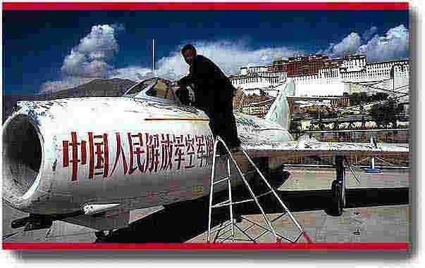 A Chinese tourist poses in front of a MIG fighter which was used to attack the Lhasa city