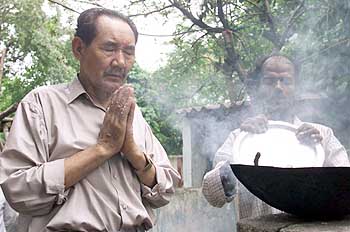 Paljor, an Eldrely Tibetan Prays Before the Food Being Served (Photo: Reuters)